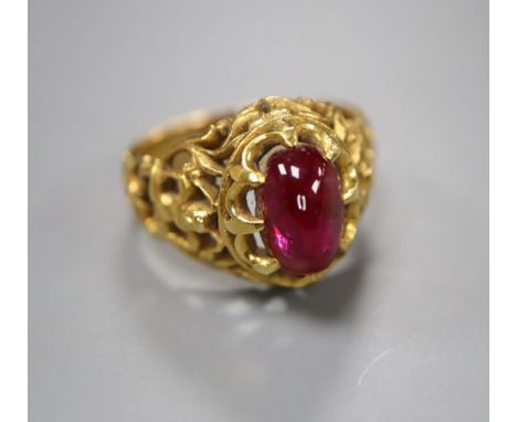 An Indian? pierced yellow metal and cabochon red stone set dress ring, size N/O, gross 8 grams.