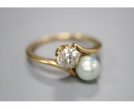 A yellow metal, diamond and cultured pearl set two stone crossover ring, size H/I, gross 2.4 grams.CONDITION: Pearl diameter 