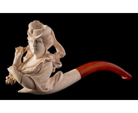 A  late 19th Century carved Meerschaum pipe: the bowl in the form  of an elegant woman wearing a stylish hat, with amber mout