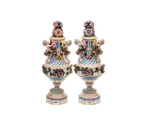 A pair of Dresden neo-classical urns and covers: each of spiral fluted form applied with putti and garlands, the cover finial