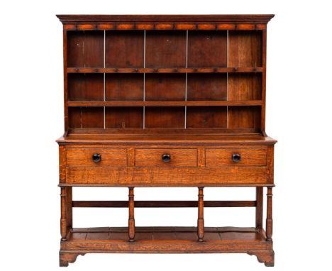 A 19th Century oak dresser:, the shelved superstructure with a moulded cornice, the base containing three short drawers on ri