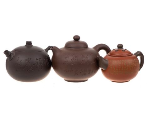 Three Chinese Yixing stoneware teapots: of various hues and of globular form with domed covers, one of which imitates a lotus