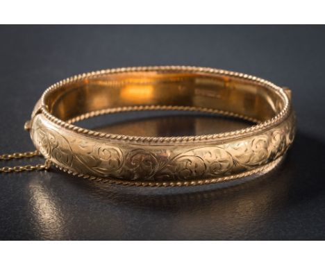 A 9ct gold hinged bangle: with attached safety chain, approximately 19gms gross weight, Chester assay marks.