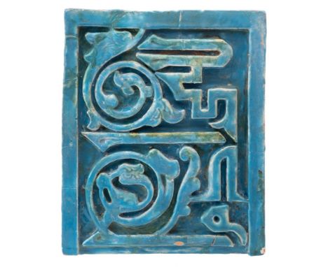 An Islamic pottery tile of Kashan type: of moulded rectangular form decorated in high relief with calligraphy under turquoise