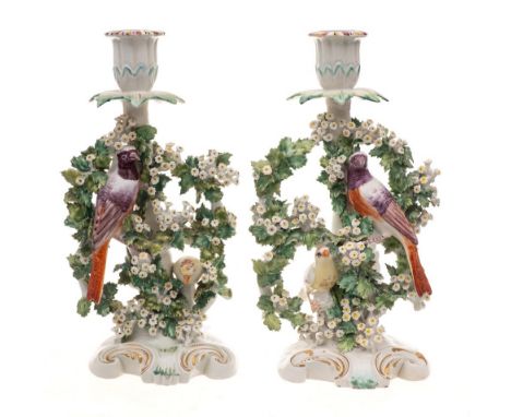 A pair of Derby 'birds in branches' candlesticks: the birds perched amongst floral bocage, on gilt heightened rocaille bases,