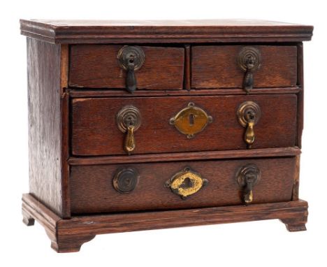 An antique miniature oak chest: of rectangular outline containing two short and two long drawers on bracket feet, 23cm wide. 
