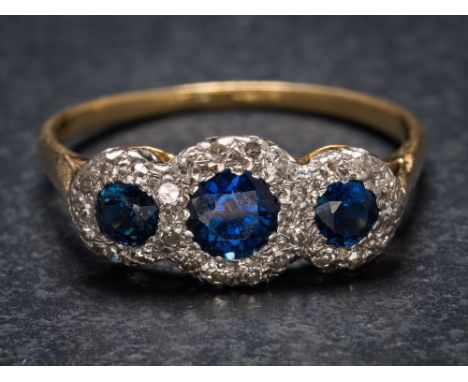 A sapphire and diamond triple cluster ring: the graduated circular sapphires within a surround of single-cut diamonds, total 