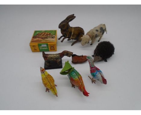 A collection of vintage clockwork tinplate toys in the form of animals including West German hedgehog, a dog with a shoe, coc