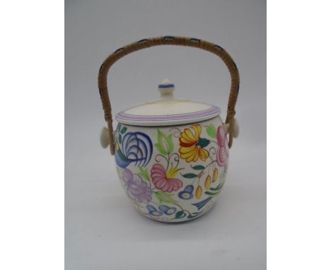 A Poole Pottery hand-decorated biscuit barrel, with finial topped cover and rattan over handle
