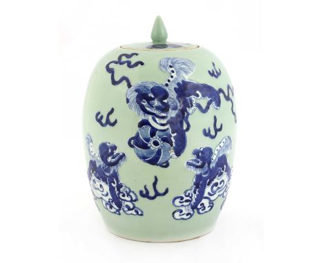 A Chinese celadon jar and cover, c.1900, of ovoid form, painted with a Buddhist lion playing with a brocade ball with its pup