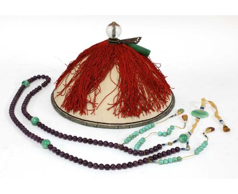 A Chinese official's hat, with a glass ball finial and a jade tube ornament, above red tassels covering the circular domed to