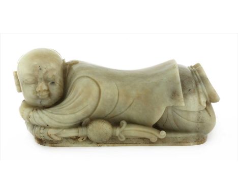 A Chinese jade pillow, of a recumbent boy lying on his stomach with a brocade ball in his right hand, his left arm supporting