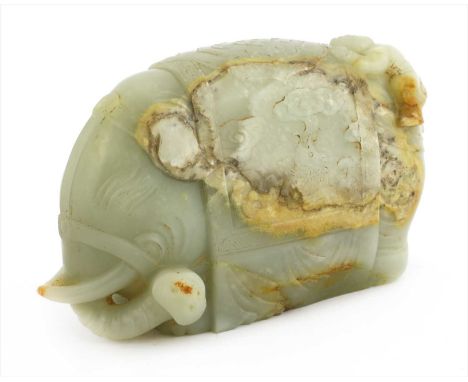 A Chinese jade carving, with a boy holding a brush, crouched on the back of an elephant, its caparison with carp amongst wave