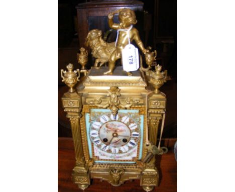 A good quality gilt and porcelain antique mantel clock with striking movement, having Ram's head and figural child and dog su