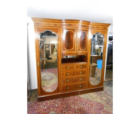 Edwardian flame mahogany and inlaid triple wardrobe compactum armoire raised on a plinth base with central bow fronted cupboa