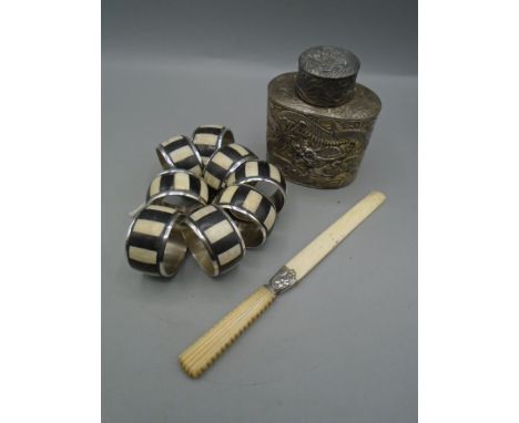 An Oriental white metal tea caddy, 8 napkin rings, an ivory ? page turner