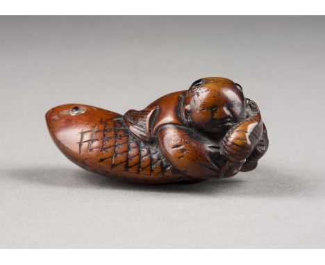 EIN HOLZGESCHNITZTES NETSUKE EINES KARAKO MIT EINEM KARPFEN Japan, 18./ 19. Jahrhundert Holz. L. 5,8 cm. Das Netsuke ist als 