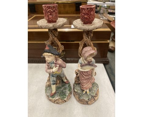 A PAIR OF CERAMIC CANDLE HOLDERS DEPICTING A BOY AND A GIRL 