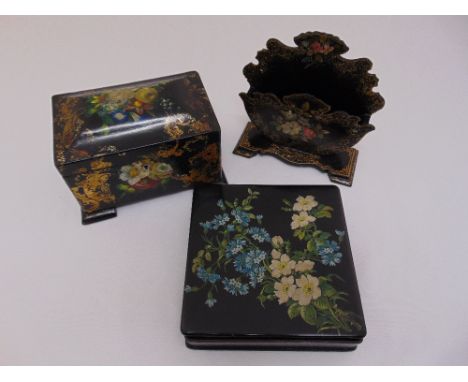 A Victorian papier-mâché tea caddy, letter rack and box with cover all decorated with floral sprays (3)
