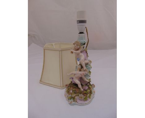 A continental porcelain table lamp in the form of putti and flowers with silk shade
