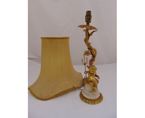 An ormolu and marble table lamp with applied putti holding a trident on tapering cylindrical base to include shade
