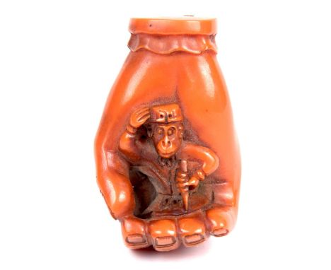 A Japanese simulated amber netsuke, 20th Century Modelled depicting Hanuman, seated within an openwork hand, signed to base, 