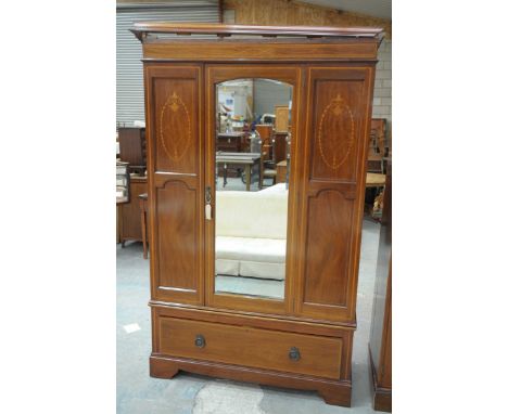 An Edwardian inlaid mahogany wardrobeHaving an inlaid and cross banded moulded cornice above a central bevelled mirrored door