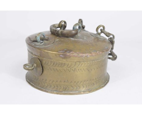 A Tibetan incised brass prayer box Of rounded form with chain work hinges, with rounded handle and round lock plate, 9cm high