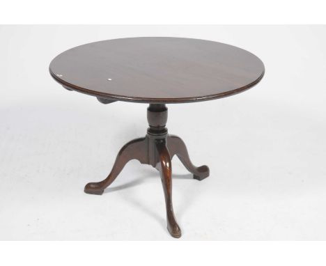 An 18th Century oak tripod tableThe circular top supported on a baluster shaped shaft with three down swept supports and pad 