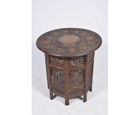 A carved Middle Eastern table The central brass inlaid roundel (possibly for a hookah) encircled by a series of fruiting vine