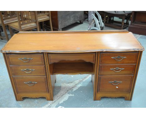 A modern cherry wood knee hole dressing tableHaving a shaped moulded top above an arrangement of seven drawers and a central 