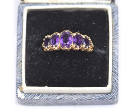 A 9ct gold amethyst five stone ringThe graduated oval shape amethyst line within a scrolling surround, ring size M, weight ap