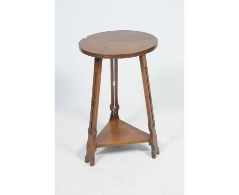 An early 20th Century oak arts and crafts occasional tableThe circular top supported on three uprights each pierced with styl