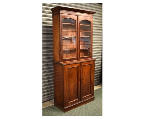 19th Century mahogany bookcase on cabinet, the upper section with arch-glazed twin doors enclosing three adjustable shelves, 