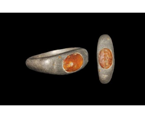 3rd century AD. A narrow D-section silver hoop with flat shoulders and scaphoid plaque, inset glass cloison with intaglio ima