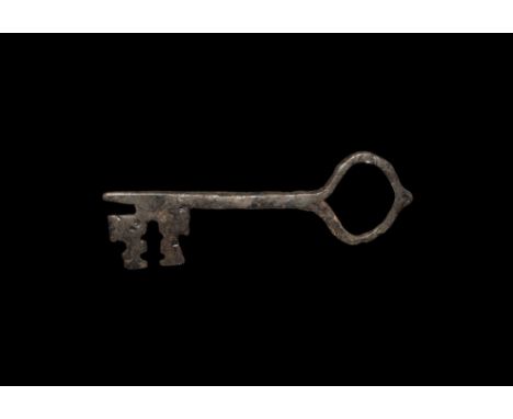 14th-15th century AD. A hand-forged iron shank with large flat-section bit, cross-shaped median breach and two wards, looped 