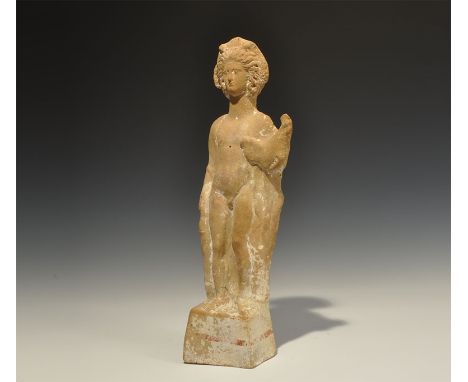 4th-1st century BC. A terracotta figure of a youthful male standing on a square pedestal, traces of a red strip of pigment an