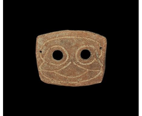 4th-3rd century BC. A rectangular slightly curved ceramic mask with two eye-holes and incised stylised facial details; pierce