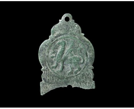 11th-14th century AD. A cast flat-section D-shaped plaque with scrolled edges, pierced lug above; to the centre a raised ring