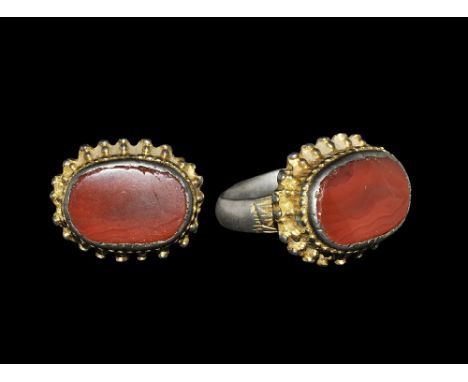 13th-14th century AD. A silver-gilt ring with carnelian cabochon set in a raised head decorated with a border of applied bead