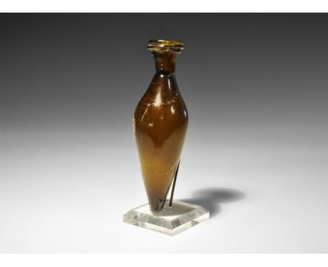 7th-8th century AD. A biconical amber-coloured glass flask with rounded tapering base, constriction ring to the neck, flared 