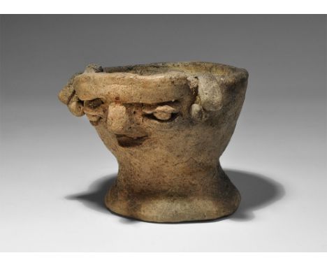Neolithic, 6th-4th millennium BC. A squat terracotta lamp or libation cup with flared base, applied facial details to the bow