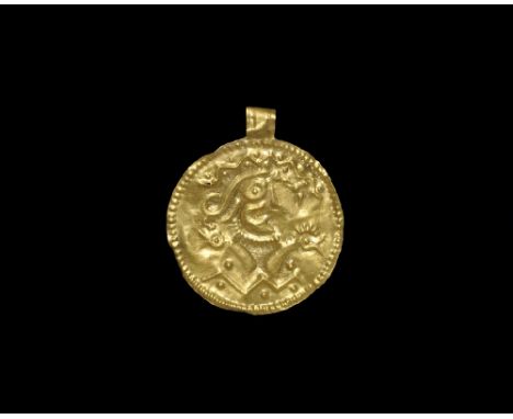 6th century AD. A broad repoussé gold-foil bracteate of Hauck's Type C with outer band of punched pellets, ribbed loop; repou