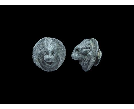 13th-15th century AD. A bronze discoid plaque with stud to the reverse, facing lion mask modelled in high relief with open mo