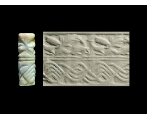Circa 2200 BC. A white marble cylinder seal with an eagle gripping two horned beasts above a hatched panel; accompanied by a 