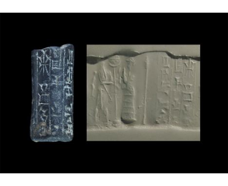 4th-2nd millennium BC. A haematite cylinder seal depicting a robed figure in conical headdress with hands raised towards a st