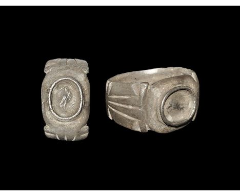 3rd century AD. A broad silver hoop with incised strokes to the shoulders, flat plaque with raised discoid cell, standing fig