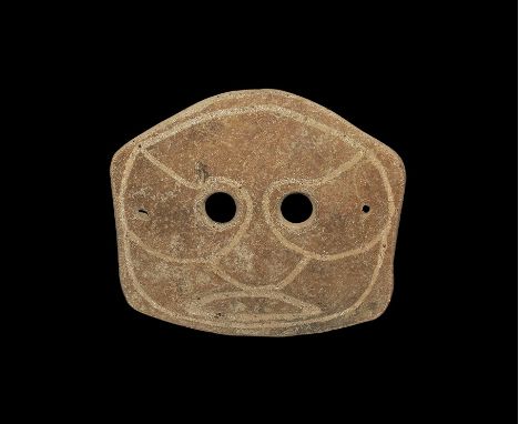 4th-3rd century BC. A pentagonal slightly domed ceramic mask with two eye-holes and incised stylised facial details; pierced 