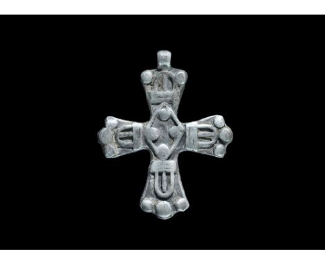 10th-12th century AD. A flat-section silver cruciform pendant with integral loop, each arm with a D-shaped raised plaque and 