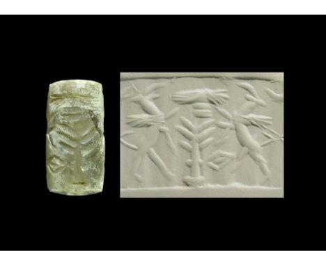8th-6th century BC. A chalcedony cylinder seal with sacred tree flanked by rearing monsters and solar disc; accompanied by a 